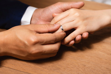 Man wearing the wedding ring to woman finger.