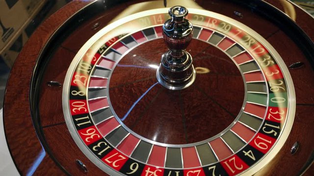 Casino: Roulette in Las Vegas with a white ball. The dealer croupier stops the roulette wheel and throws a game ball. The ball falls on the red field 34 thirty four. Close-up. Top view