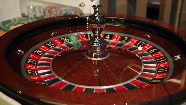 Casino: Roulette in Las Vegas with a white ball. The dealer croupier stops the roulette wheel and throws a game ball. The ball falls on the red field 34. Close-up. 4K video