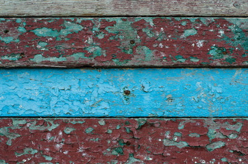 The old painted wall. The structure of the old paint. The paint is climbing off the wall. Wooden wall.