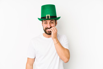 Young caucasian man wearing a saint patricks hat isolated biting fingernails, nervous and very anxious.