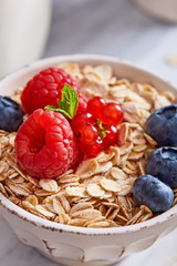 Oat meal healthy breakfast in a bowl with berrry fruits on a marble background. 