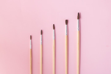 Paintbrushes isolated on pink paper, copy space