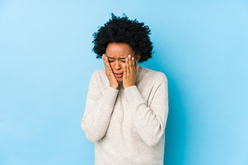Fototapeta na wymiar Middle aged african american woman against a blue background isolated whining and crying disconsolately.