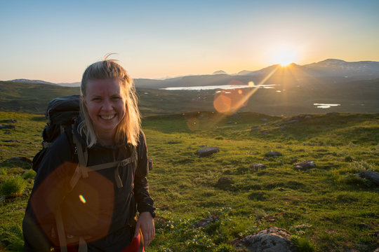 Open landscape of Midnight sun in Lapland Northern Sweden, Europe. Happy Female Hiker enjoy the Midnight Sun north of the Arctic Circle.