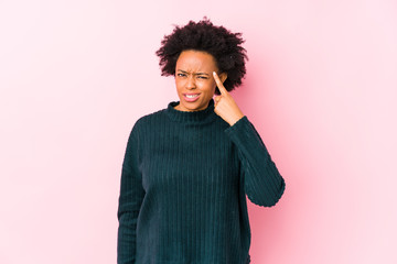 Fototapeta na wymiar Middle aged african american woman against a pink background isolated showing a disappointment gesture with forefinger.