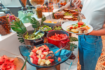 Woman choosing food in open buffet at breakfast in hotel