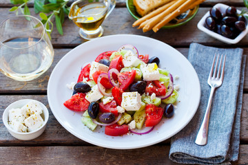 Greek salad. Fresh vegetables, feta cheese and black olives with white wine. Close up.