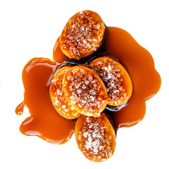 Sweet candies with salt caramel topping isolated  on white background. Toffee with caramel sauce close-up. Top view..