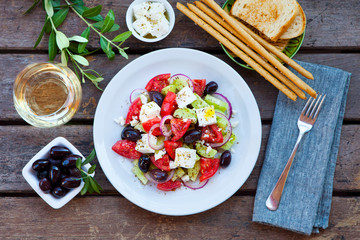 Greek salad. Fresh vegetables, feta cheese and black olives with white wine. Top view.