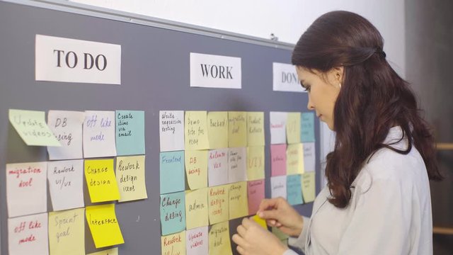 attractive scrum master putting sticky note with ui lettering on board 