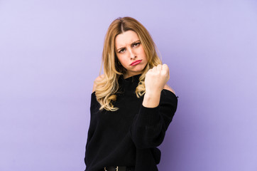 Young blonde woman isolated showing fist to camera, aggressive facial expression.