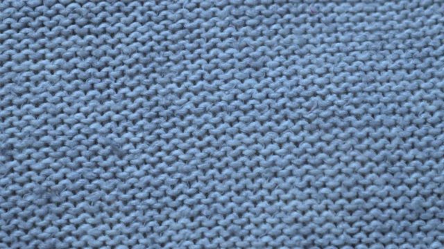 Close-up of blue knitted wool fabric texture, camera slide.