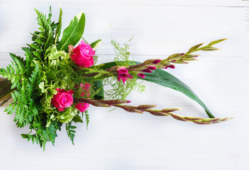 Bouquet composition with pink rose and gladiolus on black wooden background