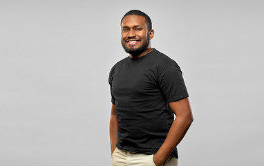 people concept - happy smiling young african american man in black t-shirt over grey background