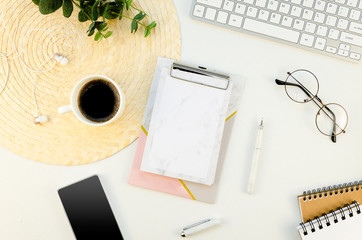 Workspace with Paper A4 clipboard mockup. Top view feminine desk with keyboard, notebook, phone, keyboard, glasses and eucalyptus