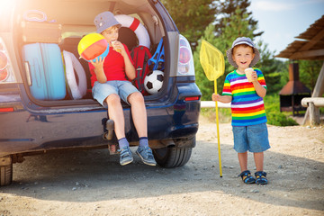 child sitting in car filled with traveling accessories