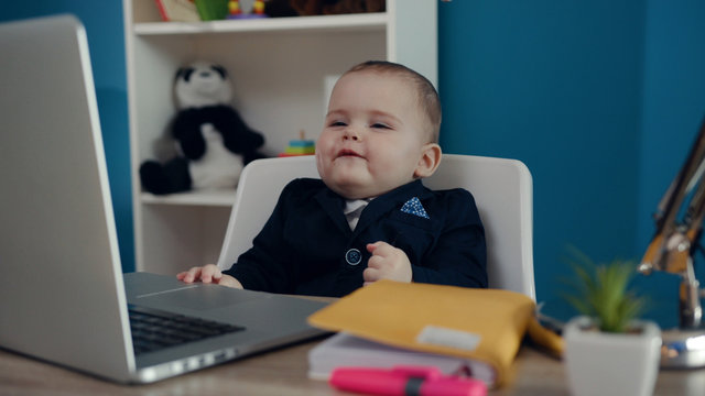 Charming little boy businessman boss in office use laptop write notebook sitting play creative happy job work child computer education young suit cute career confident close up slow motion.