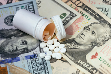 White pills scattered on money notes