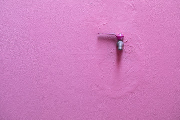 The faucet is installed on the pink wall