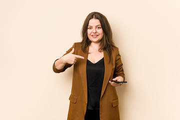 Young curvy woman holding a phone person pointing by hand to a shirt copy space, proud and confident