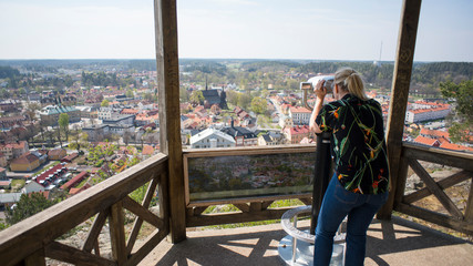 Tourist woman using binoculars on lookout point overlooking City of Soderkoping in Sweden, Europe.