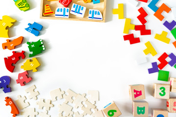 Colorful baby toys on white background. Frame from developing wooden blocks, cars and puzzles. Natural, eco-friendly toys for children. Top view. Flat lay. Copy space.