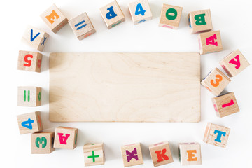 Kids toys wooden cubs with letters and numbers on white background. Frame from developing wooden blocks. Natural, eco-friendly toys for children. Top view. Flat lay. Copy space.