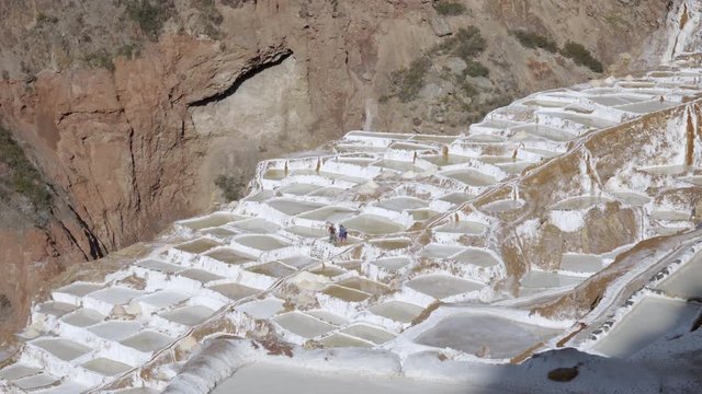 Salinas de Maras in the Sacred Valley of the Incas in the Andes Mountains of Cusco Region, Peru - Salt workers in salt pods 