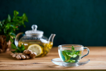 Fresh mint herbal tea in glass teapot and cup, front view