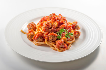 Plate of spaghetti with tomato and meatballs with parsley leaves