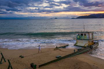 Nha Trang, Vietnam sunrise featuring south China Sea, East Sea, distant islands and a ship wreck in the foreground beach
