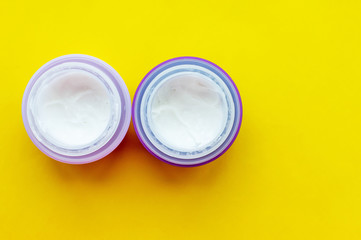 Gray jars with face cream on a yellow background. Skin care.