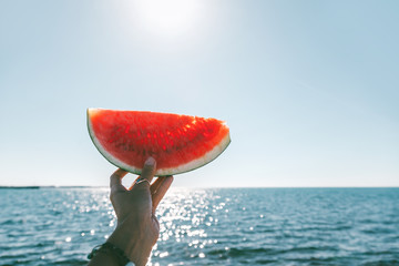 Watermelon slice in woman hand over sea