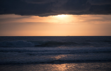 Beautiful minimalism is a seascape. Waves on a background of orange sunset sky