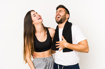 Fototapeta premium Young caucasian fitness couple isolated relaxed and happy laughing, neck stretched showing teeth.