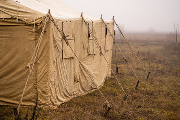 Big canvas brown tent arranged outside in foggy autumnal landscape. © Andrii Oleksiienko
