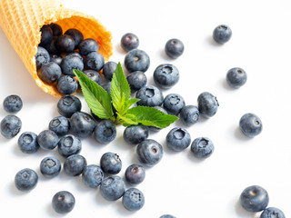 Blueberries in a waffle cone with a mint leaf. Close up fresh berries on a white background