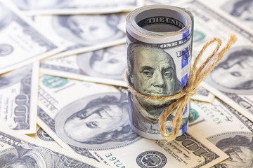 Roll of 100 dollar banknotes on dollars background