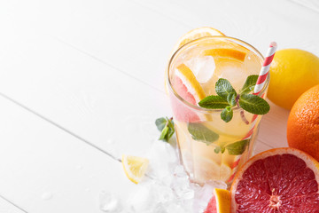 Summer refreshing lemonade with mint on a light background. A glass of citrus cocktail in a light key. Close-up. Summer Vitamin cocktail of orange, lemon and grapefruit.