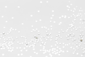 Silver confetti and stars and sparkles on a light background. Top view, flat lay. Copy text. holiday background. For Christmas, New Year, Valentine's Day