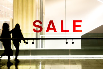 Shop window 'SALE' sign with silhouetted shoppers