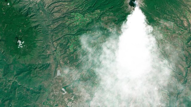 Aerial view of volcano eruption with white plume smoke, Colima Mexico. Images furnished by Nasa