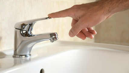 a person closes the water tap of the bathroom