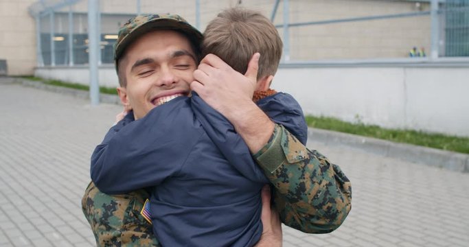 Military father hugging son.