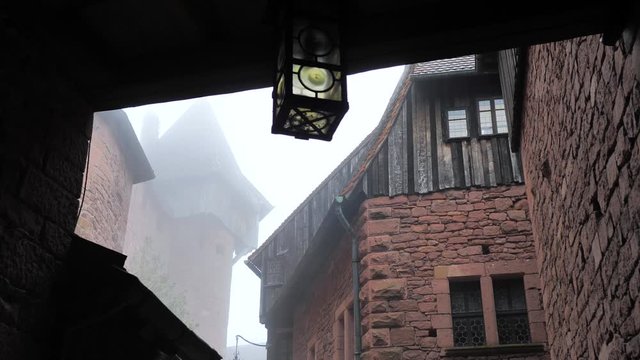 L&aacute;mpara exterior balance&aacute;ndose por el viento y la niebla dentro de castillo terror&iacute;fico