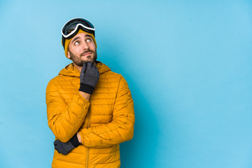 Young skier caucasian man isolated relaxed thinking about something looking at a copy space.