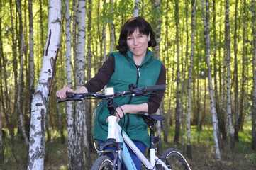 Naklejka premium Beautiful young woman On a bicycle standing in the forest against the backdrop of a birch grove. fitness