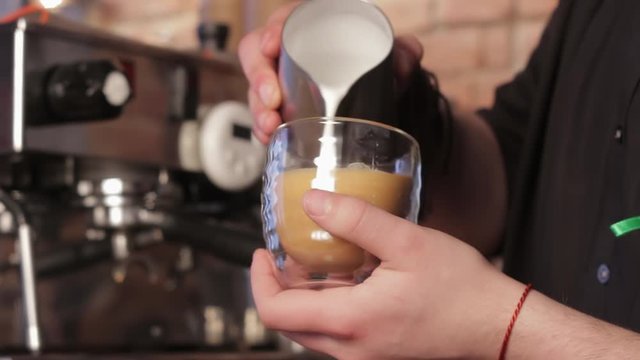 Barista making coffee latte art. Pouring milk into cappuccino. Male hand putting a cup of latte coffee on a table