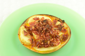 Healthy snack of melted cheese, apple slices and turkey bacon bits on tortilla on green plate with white tablecloth background